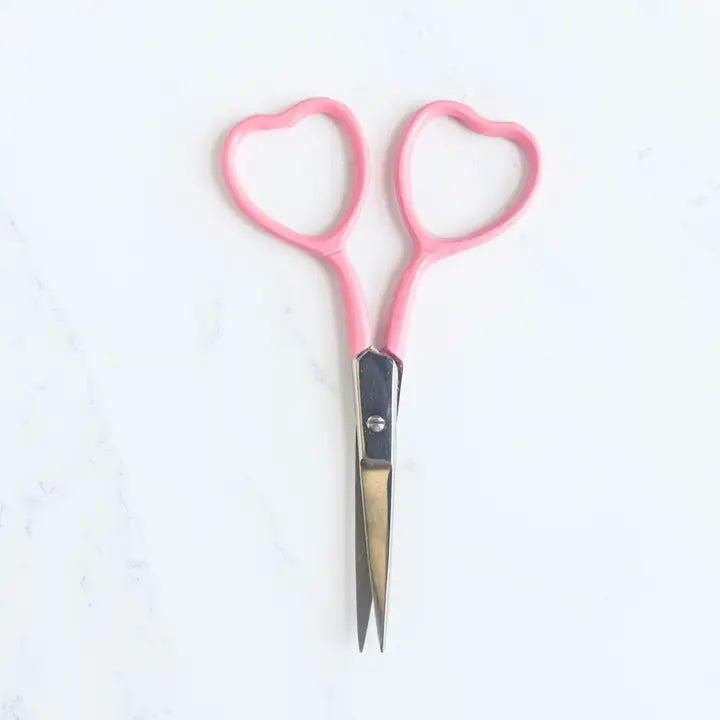 Pink-handled scissors on a white background