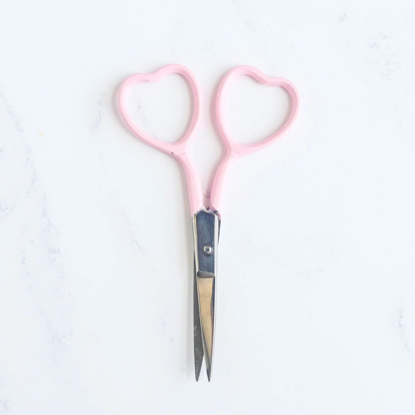Pink-handled scissors on a white background
