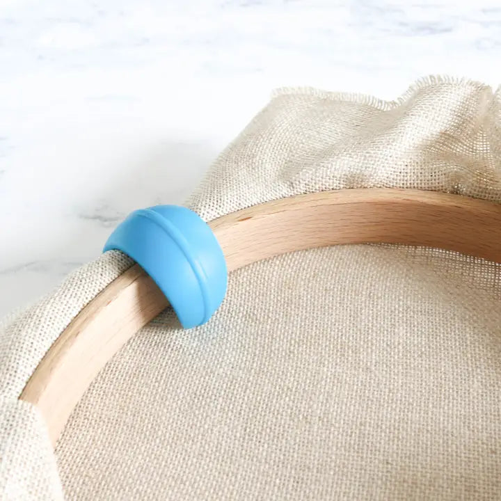 Silicone hoop huggers holding excess fabric away from the stitching area in multi colors