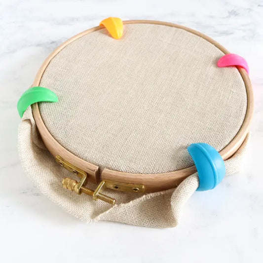 Silicone hoop huggers holding excess fabric away from the stitching area in multi colors