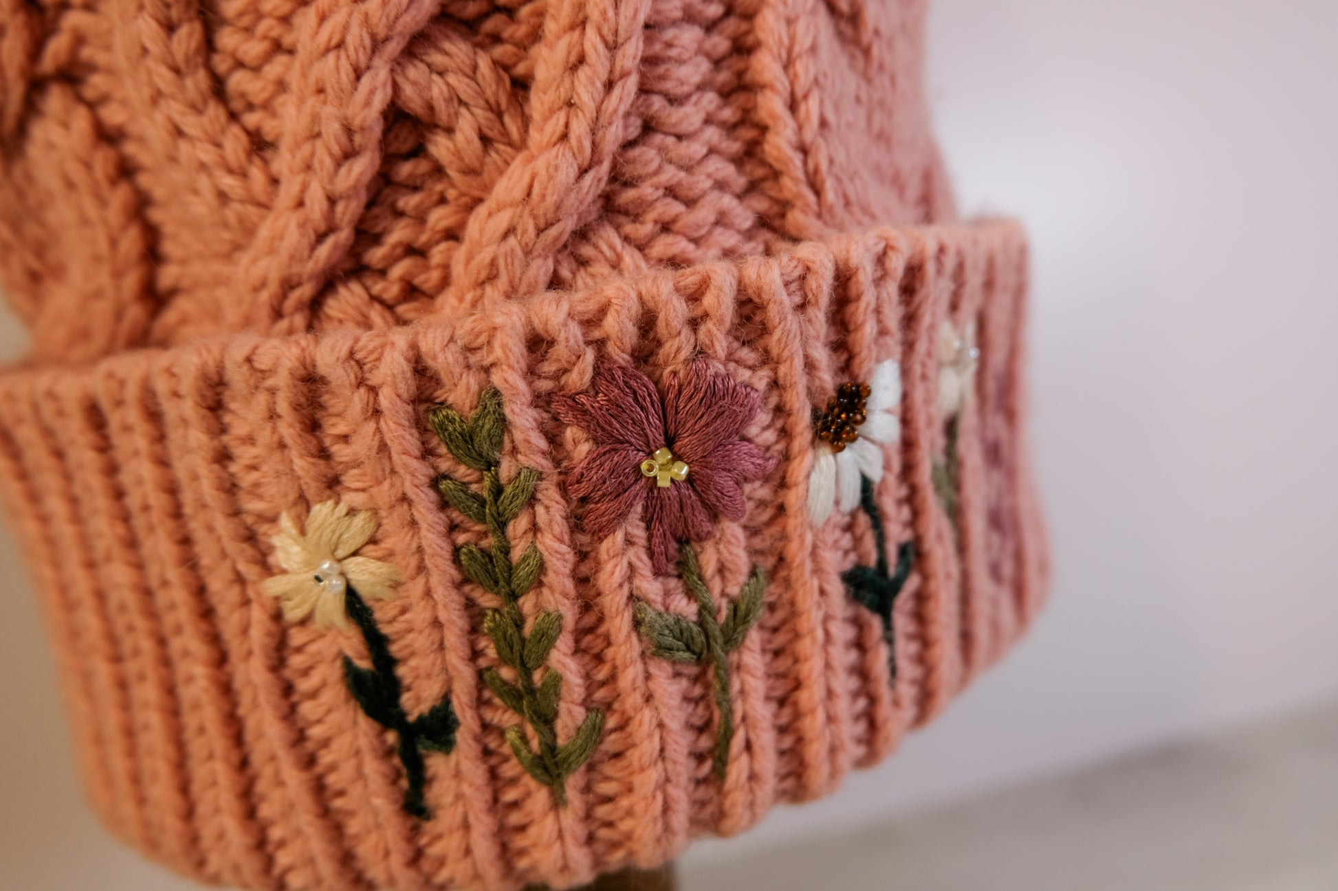 Knitted hat with floral embroidery on a plain background