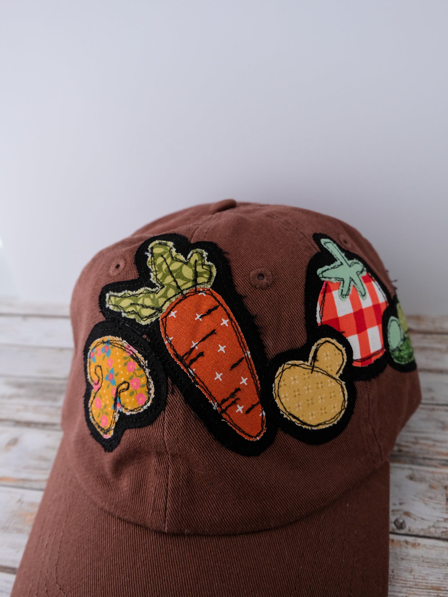 Brown cap with colorful vegetable patches on a wooden surface