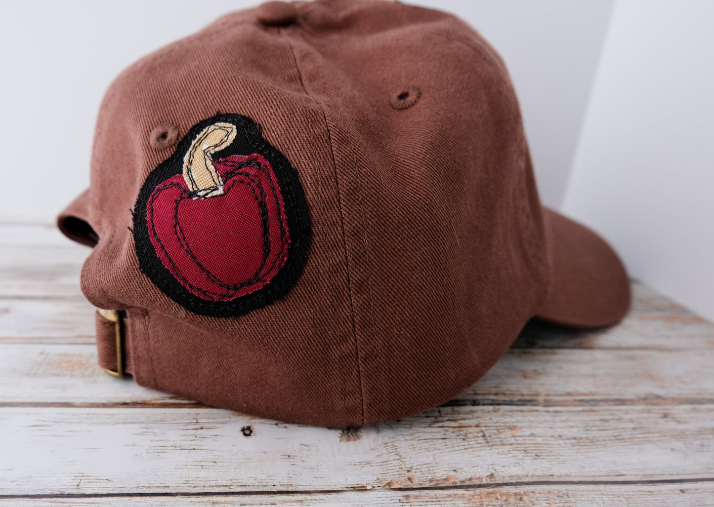 Brown cap with a red and black patch on a wooden surface