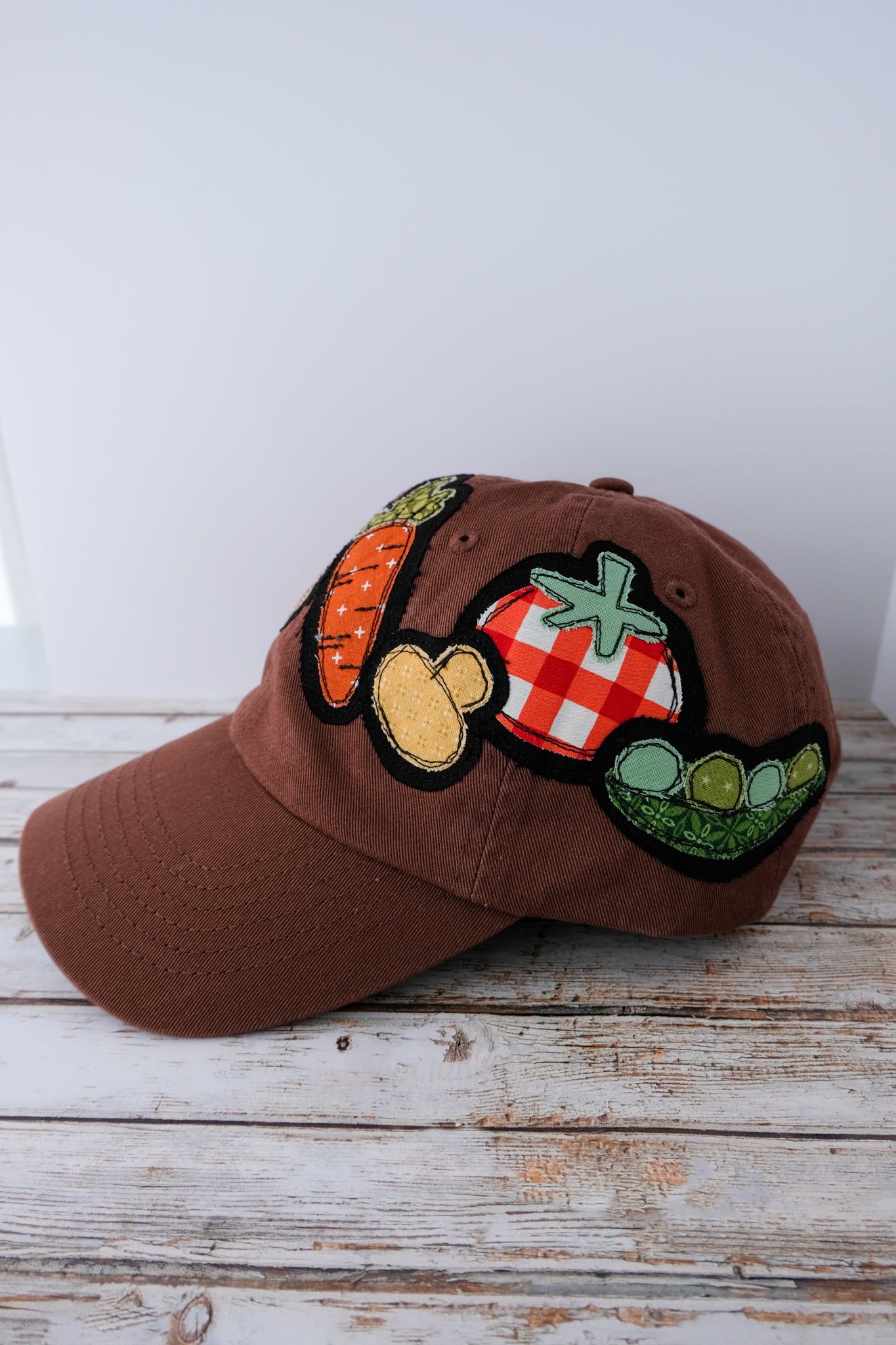 Brown cap with vegetable patches on a wooden surface