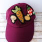 Maroon cap with vegetable patches on a wooden surface