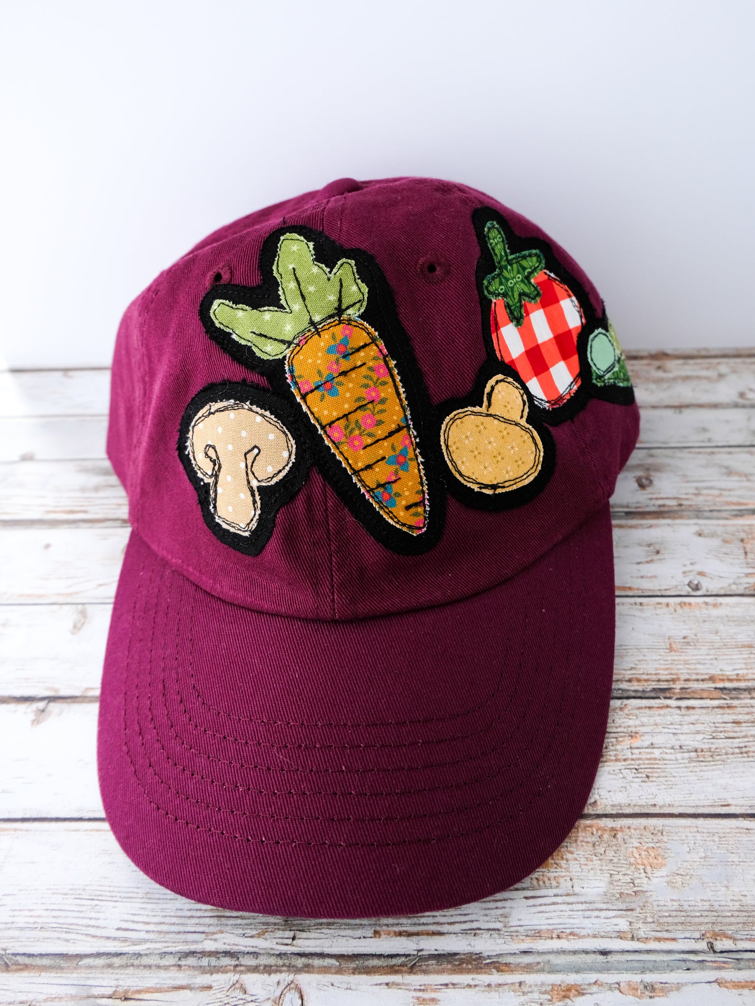 Maroon cap with vegetable patches on a wooden surface