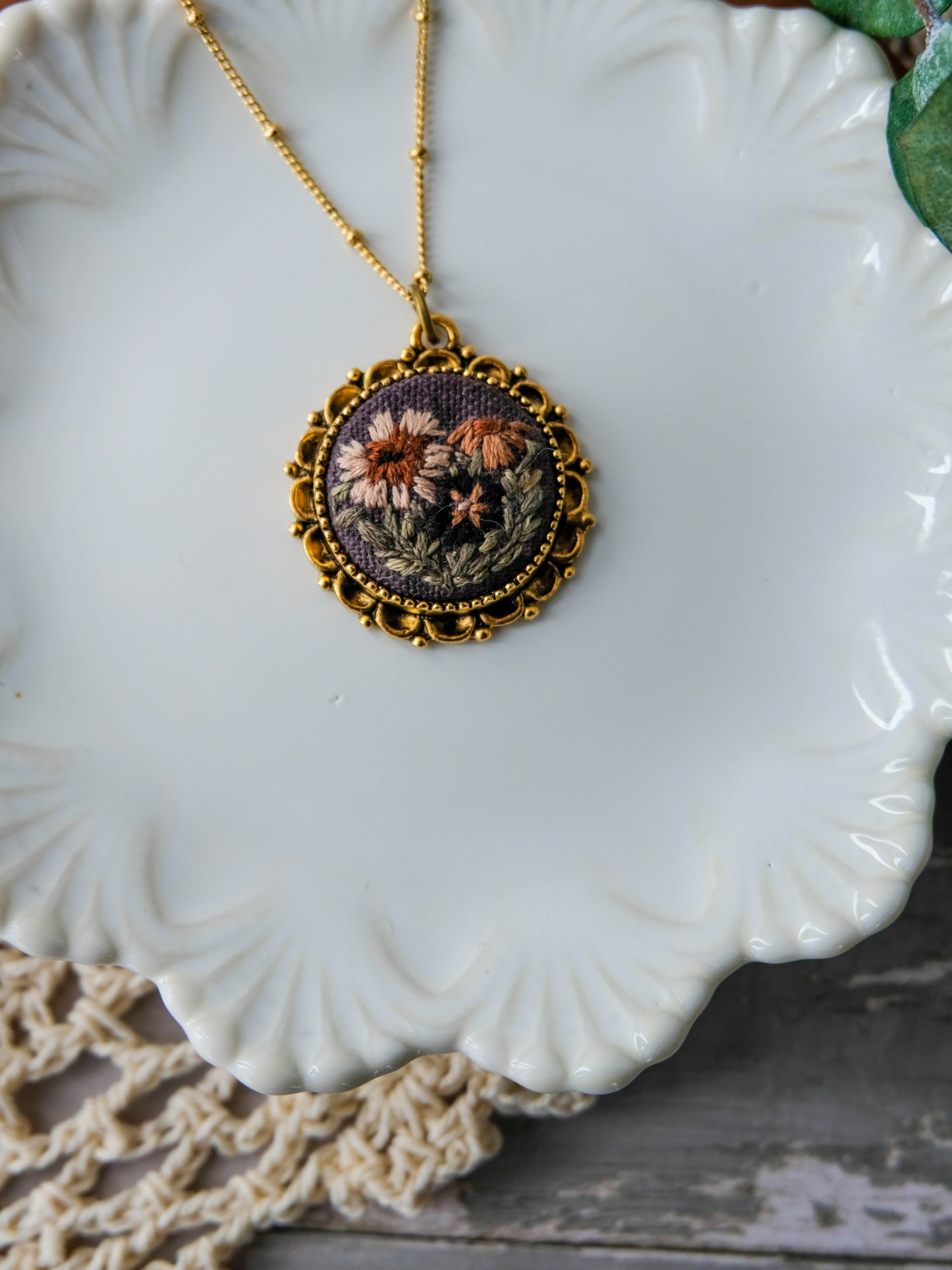 Decorative necklace with floral design on a white ceramic plate