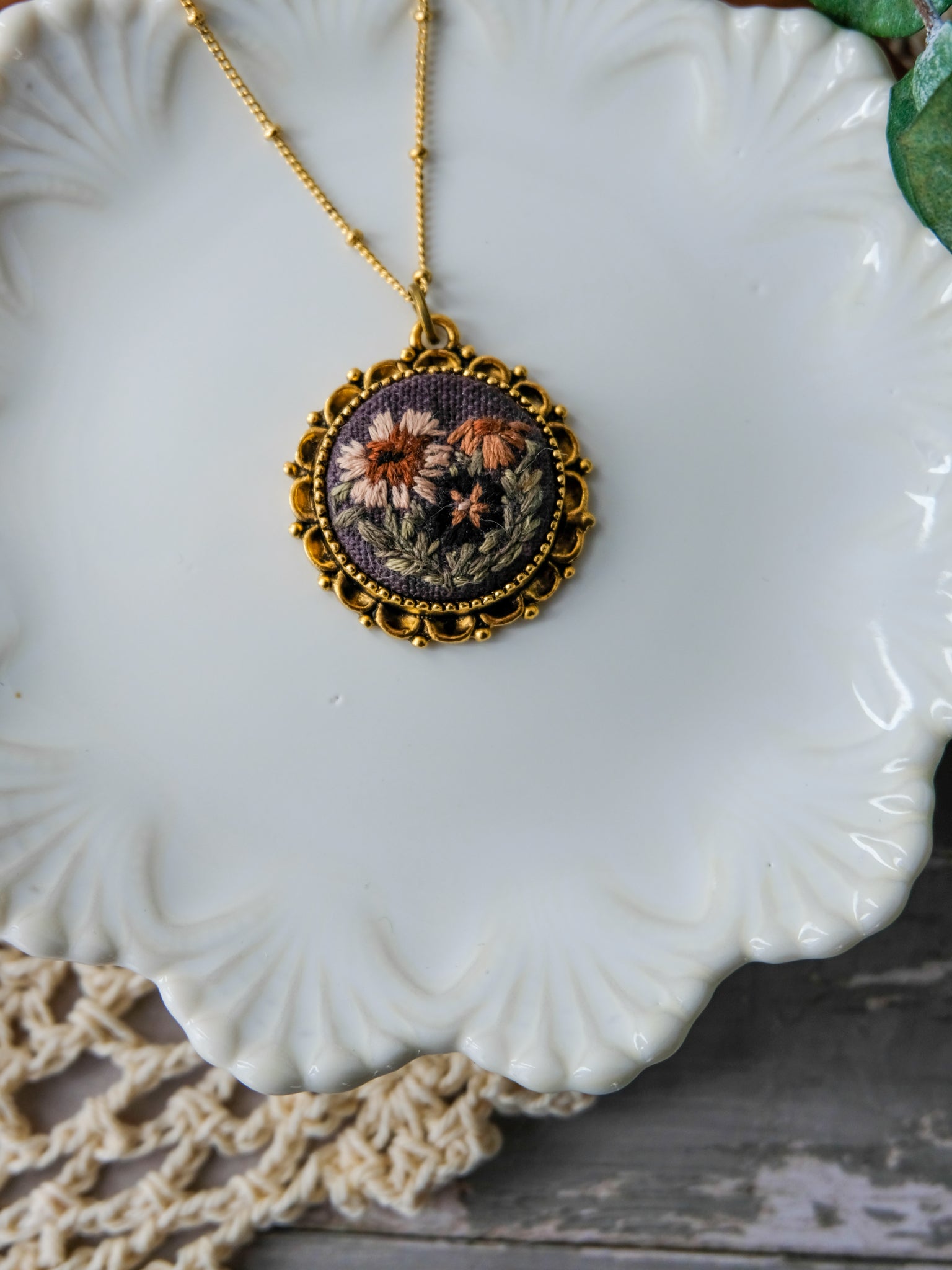 Decorative necklace with floral design on a white ceramic plate