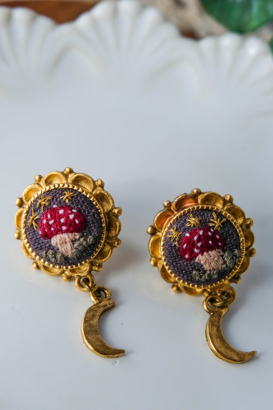 Pair of earrings with embroidered designs on a white plate