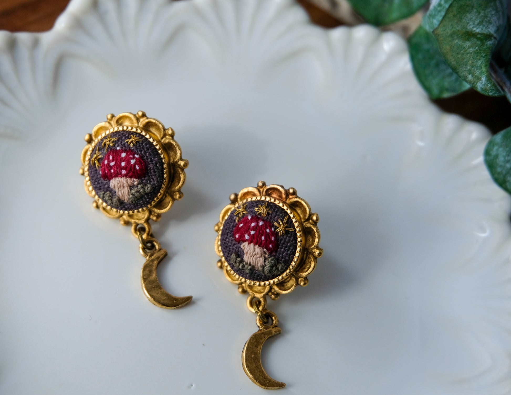 Pair of earrings with mushroom design on a decorative plate