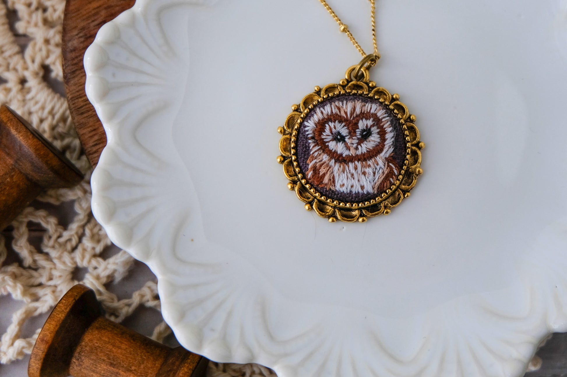 Necklace with an owl pendant on a white dish with wooden elements.