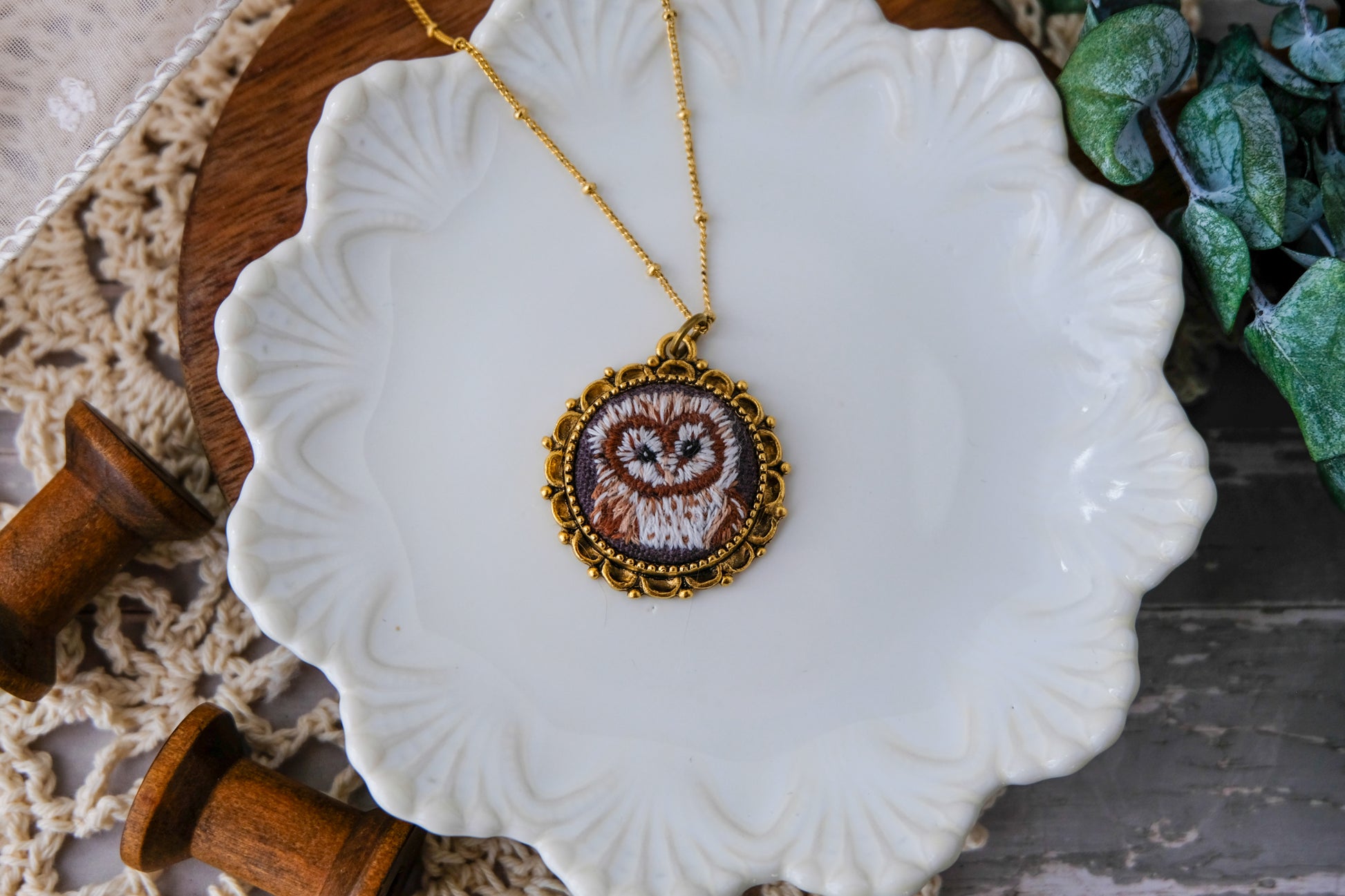 Necklace with an embroidered pendant on a decorative white plate