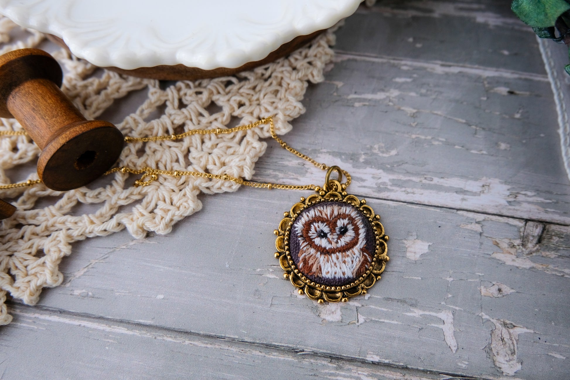Necklace with an embroidered owl pendant on a textured surface