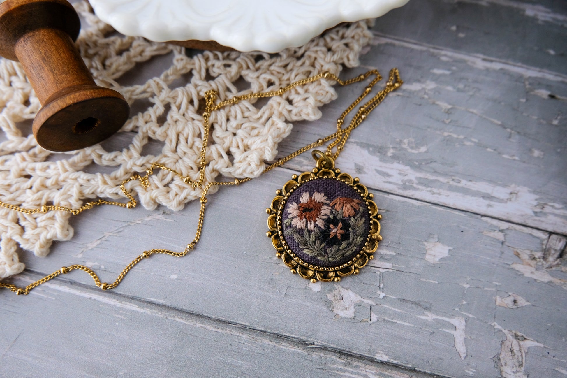 Necklace with floral pendant on a textured wooden surface