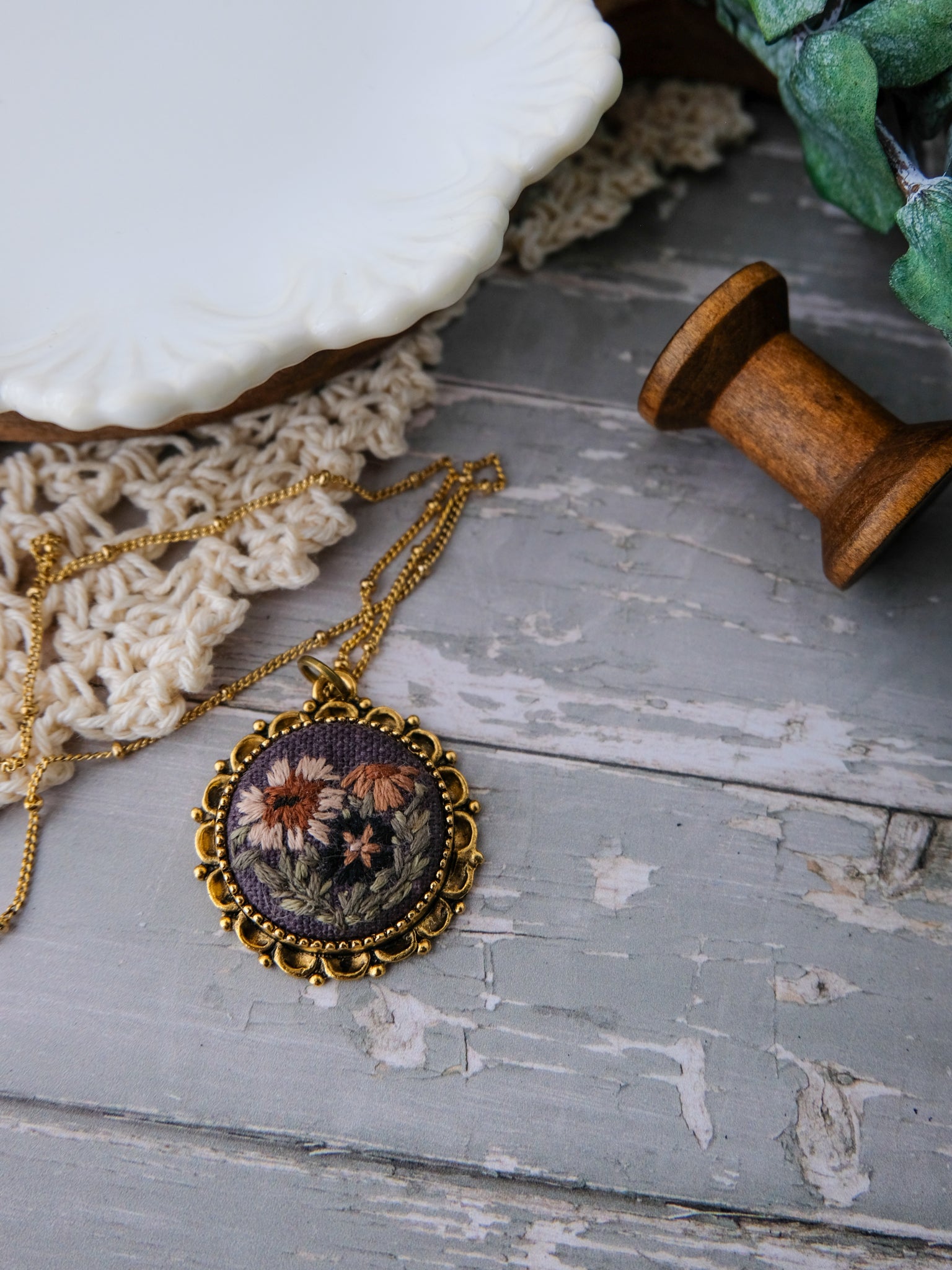 Necklace with a floral pendant on a rustic wooden surface