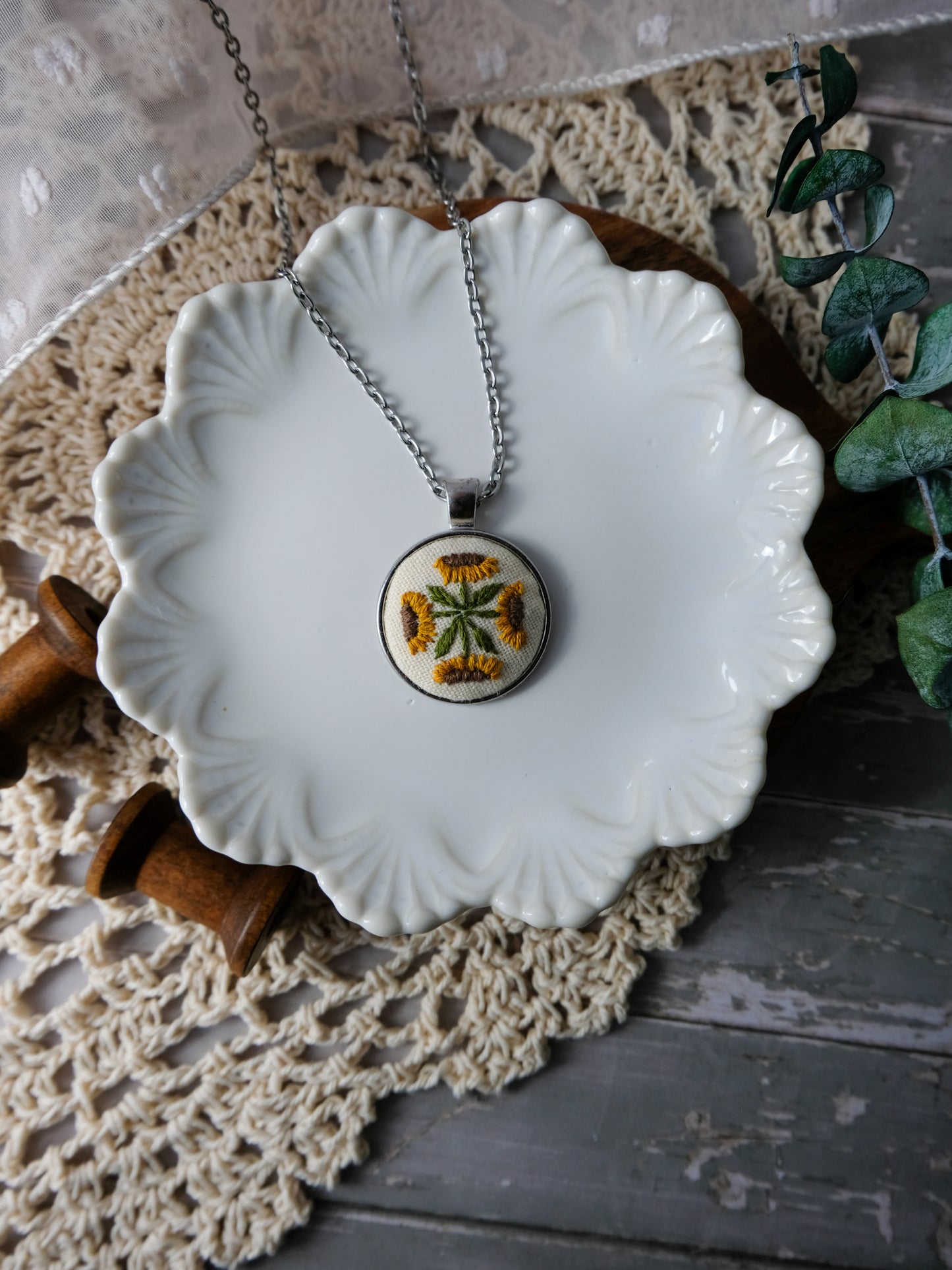 Necklace with a sunflower pendant on a white ceramic dish