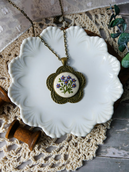 Necklace with an embroidered pendant on a white dish with a textured background