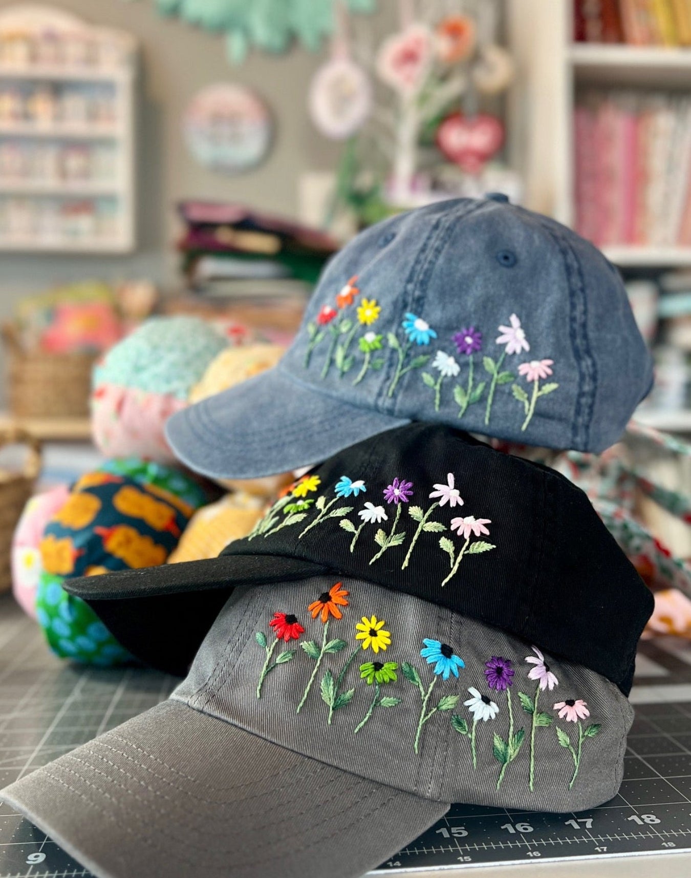 Three embroidered baseball caps on a table with a colorful background