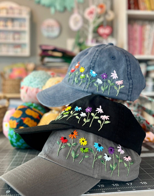 Three embroidered baseball caps on a table with a colorful background