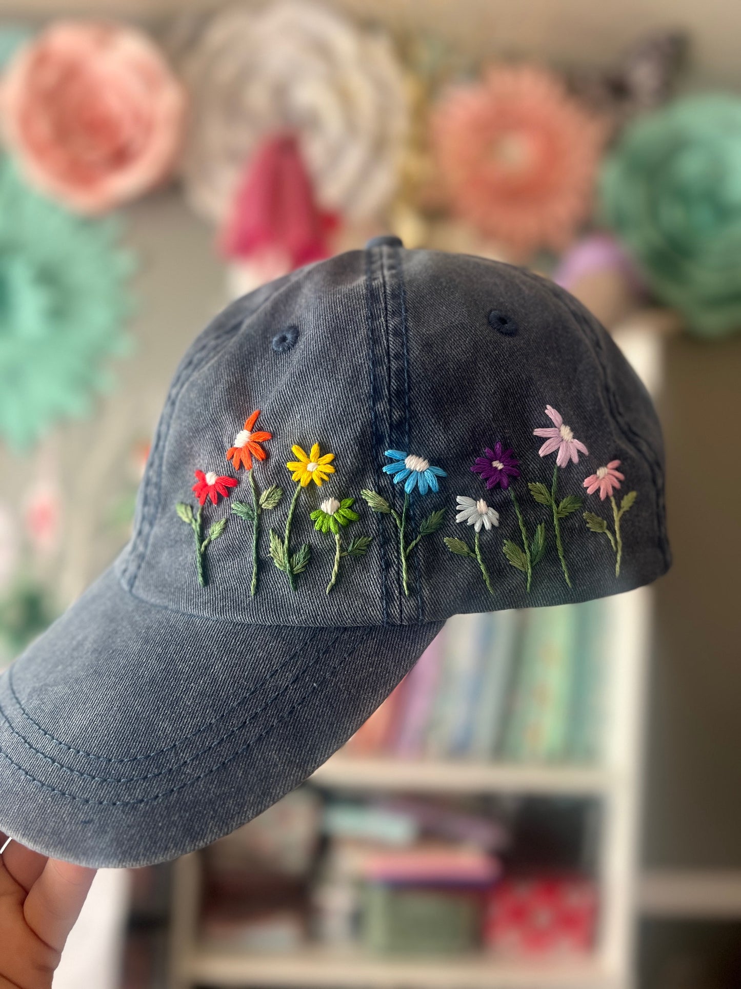 Blue cap with embroidered colorful flowers against a blurred background